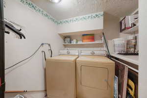Washroom with a textured ceiling and washer and clothes dryer