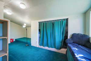 Carpeted bedroom featuring a textured ceiling and a closet