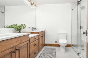 Full bath with a marble finish shower, double vanity, and light tile patterned flooring