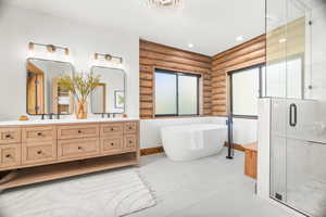 Bathroom featuring a soaking tub, rustic walls, a stall shower, double vanity, and recessed lighting