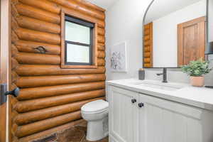 Half bath with vanity and rustic walls