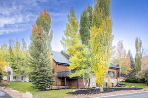 View of front facade featuring a front yard, roof with shingles, and stone siding