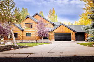Cabin with concrete driveway, log siding, and a garage