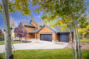 Cabin with a front yard, concrete driveway, and roof with shingles