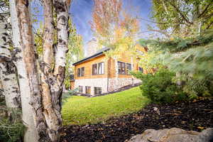 View of home's exterior with a chimney, a lawn, and stone siding