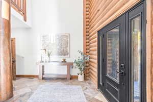 Foyer featuring stone tile floors and log walls
