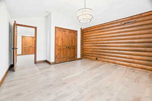 Foyer with a chandelier, vaulted ceiling, light wood-style floors, and rustic walls