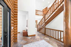 Entryway featuring stone tile floors, a towering ceiling, recessed lighting, and stairs