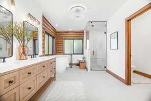 Full bathroom featuring a freestanding bath, a marble finish shower, double vanity, rustic walls, and recessed lighting