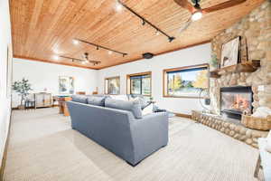 Living room featuring track lighting, a ceiling fan, wooden ceiling, carpet flooring, and a fireplace