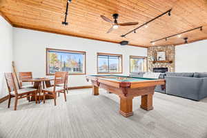 Recreation room featuring rail lighting, wooden ceiling, a stone fireplace, billiards table, and light carpet
