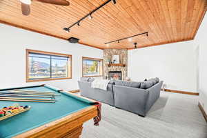Rec room featuring rail lighting, wooden ceiling, a stone fireplace, carpet, and pool table