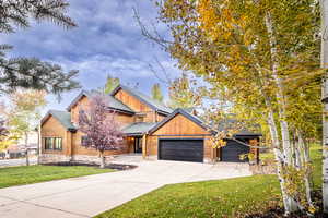 View of front of home featuring a front yard, a shingled roof, concrete driveway, and a garage