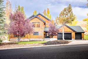Log cabin featuring concrete driveway, a garage, and log exterior
