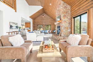 Living area with wood ceiling, recessed lighting, a stone fireplace, hardwood / wood-style floors, and high vaulted ceiling
