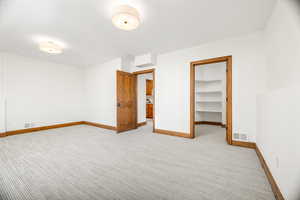 Unfurnished bedroom with a walk in closet and light colored carpet