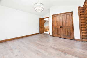 Unfurnished bedroom with vaulted ceiling, light wood-style floors, and a closet