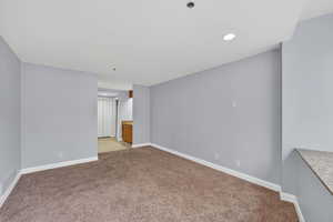 Empty room with light carpet and recessed lighting