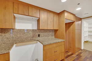 Kitchen with light wood-type flooring, light stone countertops, recessed lighting, tasteful backsplash, and modern cabinets