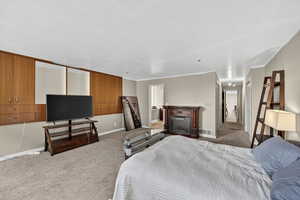 Carpeted bedroom featuring baseboards and a fireplace