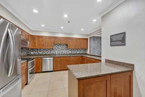 Kitchen with light stone counters, brown cabinets, stainless steel appliances, light tile patterned floors, and recessed lighting
