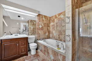 Full bath with a jetted tub, vanity, a shower stall, tile walls, and light tile patterned floors