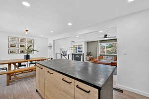 Kitchen with light brown cabinetry, a center island, dark countertops, recessed lighting, and light wood-style flooring