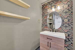 Bathroom featuring wallpapered walls and vanity