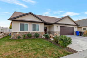 Ranch-style home featuring stucco siding, concrete driveway, a garage, and stone siding