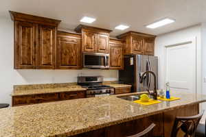Kitchen featuring stainless steel appliances, light stone countertops, and a breakfast bar area