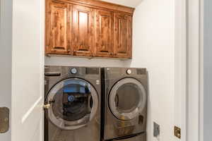 Washroom featuring cabinet space and washer and clothes dryer