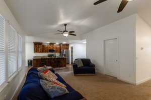 Living room with ceiling fan, vaulted ceiling, and carpet floors