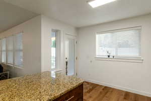 Kitchen featuring light wood finished floors, light stone counters, and dark brown cabinets