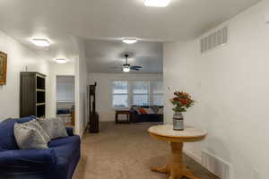 Carpeted living area with a textured ceiling and ceiling fan