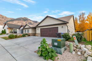 Single story home featuring a mountain view, driveway, stucco siding, an attached garage, and stone siding
