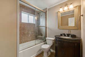 Full bathroom featuring vanity, shower / bath combination with glass door, and crown molding