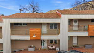 Rear view of property with roof with shingles and a balcony
