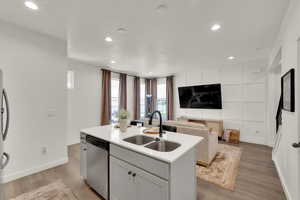 Kitchen with light stone countertops, appliances with stainless steel finishes, light wood-style flooring, recessed lighting, and open floor plan