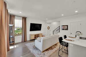 Living room with light wood finished floors, recessed lighting, and a decorative wall