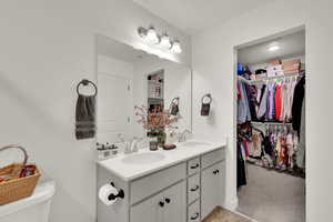 Bathroom featuring double vanity, a spacious closet, and light colored carpet