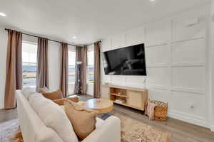 Living room featuring a decorative wall, light wood-style flooring, and recessed lighting