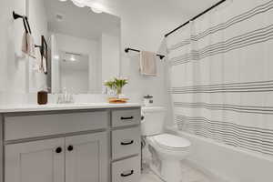 Full bathroom with light tile patterned flooring, shower / bathtub combination with curtain, and vanity