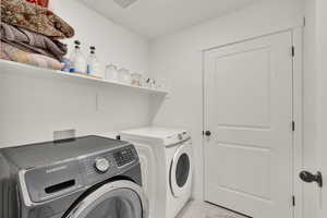 Washroom featuring washer and clothes dryer and light marble finish flooring