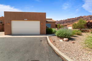 Pueblo-style house featuring stucco siding, a garage, a mountain view, and driveway