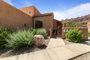 View of exterior entry with a tiled roof, a gate, stucco siding, and a mountain view