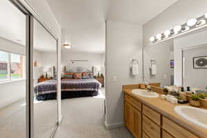 Full bath featuring connected bathroom, double vanity, and light carpet