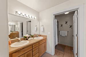 Bathroom featuring double vanity, light tile patterned floors, and curtained shower