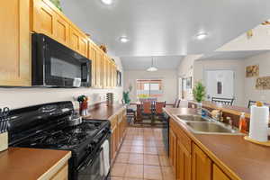 Kitchen featuring black appliances, hanging light fixtures, light tile patterned flooring, and recessed lighting