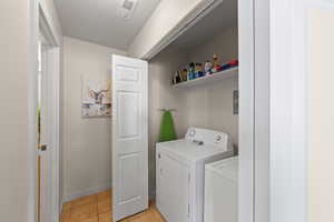 Laundry area featuring light tile patterned flooring and washing machine and clothes dryer