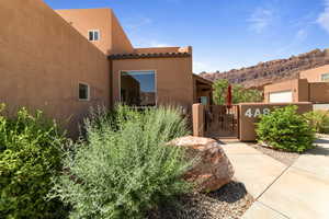 View of side of home featuring a gate, a mountain view, stucco siding, and a tiled roof